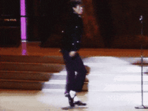 A Person Is Dancing On A Stage In Front Of A Microphone GIF