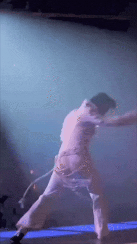 A Person Is Dancing On A Stage With A Purple Background GIF