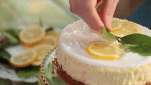 A Person Is Decorating A Cake With Lemon Slices And A Lime . GIF