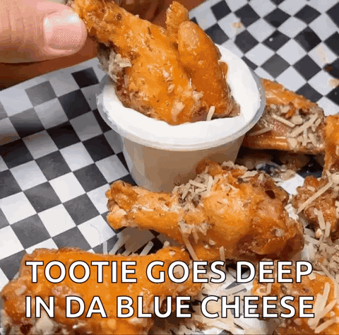 A Person Is Dipping A Chicken Wing Into A Sauce That Says " Tootie Goes Deep In Da Blue Cheese " GIF