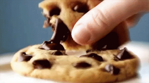 A Person Is Dipping A Chocolate Chip Cookie In Chocolate Sauce GIF