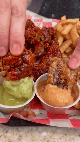 A Person Is Dipping A Piece Of Fried Chicken Into Guacamole Sauce GIF