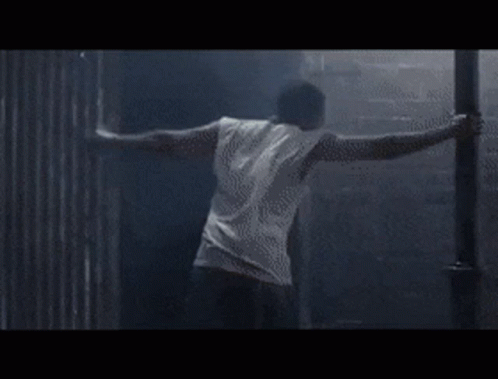 A Person Is Doing A Handstand In A Dark Room . GIF