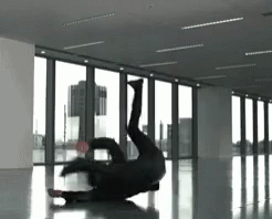 A Person Is Doing A Handstand In A Room With A Lot Of Windows GIF