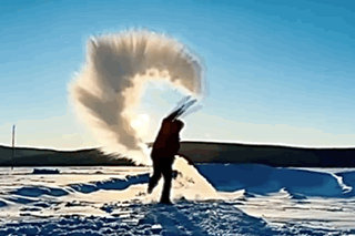 A Person Is Doing A Handstand In The Snow In Front Of A Large Explosion Of Snow GIF