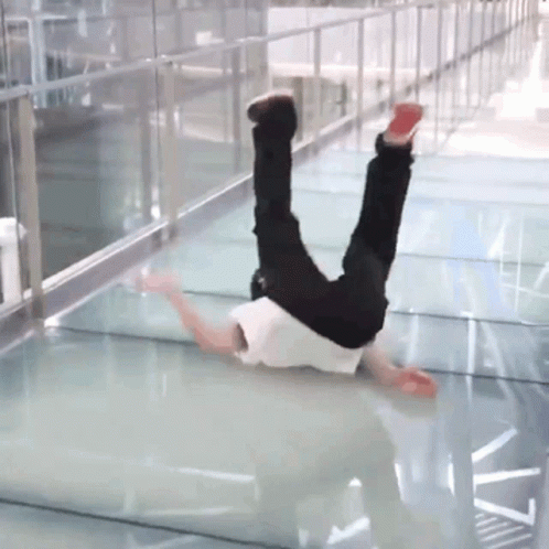 A Person Is Doing A Handstand On A Glass Walkway GIF