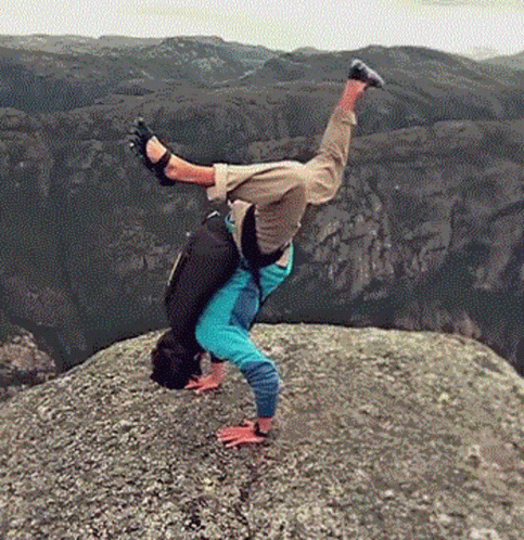 A Person Is Doing A Handstand On A Rocky Cliff . GIF