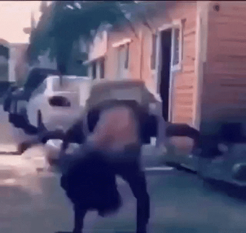 A Person Is Doing A Handstand On A Sidewalk In Front Of A Building . GIF