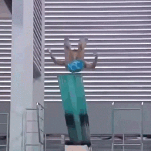 A Person Is Doing A Trick On A Diving Board In A Pool . GIF