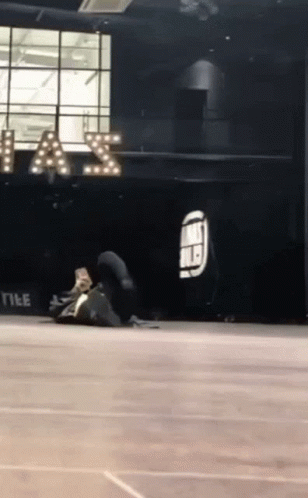 A Person Is Doing A Trick On The Floor In Front Of A Sign That Says " A & S " GIF