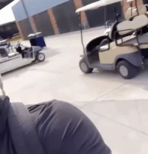 A Person Is Driving A Golf Cart In A Parking Lot GIF
