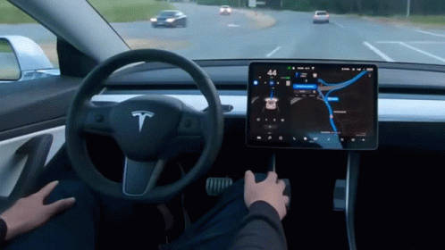 A Person Is Driving A Tesla Model 3 With The Time Of 4:44 GIF