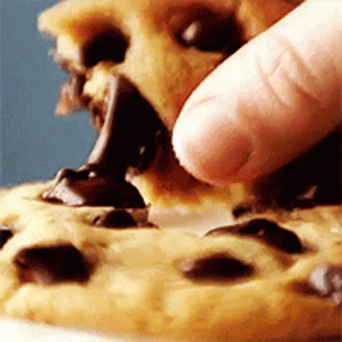 A Person Is Eating A Chocolate Chip Cookie With Their Fingers GIF