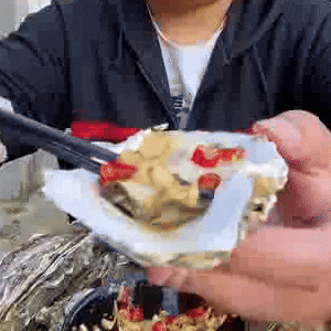 A Person Is Eating Oysters With Chopsticks And A Spoon . GIF