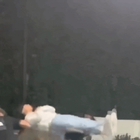 A Person Is Flying Through The Air While A Group Of People Watch . GIF