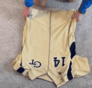a person is folding a yellow jersey with the number 14 on it