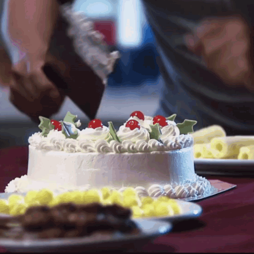 A Person Is Frosting A Cake With Whipped Cream And Cherry Decorations GIF