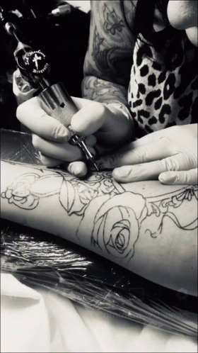 A Person Is Getting A Tattoo On Their Arm With A Machine That Has A Cross On The Top GIF