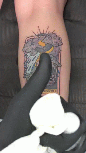 A Person Is Getting A Tattoo On Their Leg That Says ' Thinker ' GIF