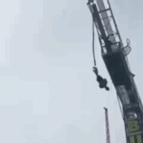 A Person Is Hanging Upside Down From A Bungee Tower . GIF
