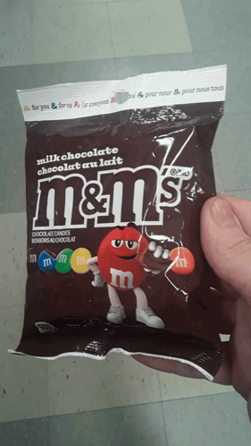 A Person Is Holding A Bag Of M & M 'S Milk Chocolate GIF