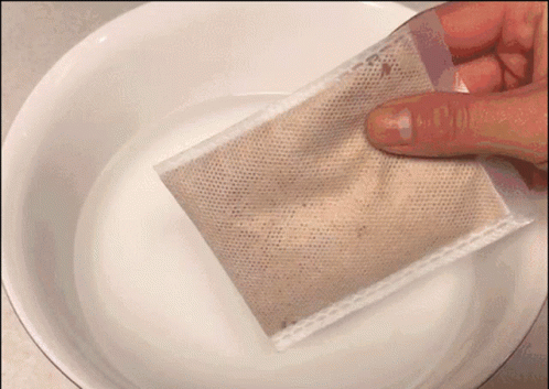 A Person Is Holding A Bag Over A Bowl Of Liquid GIF