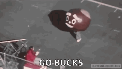 A Person Is Holding A Balloon That Looks Like A Poop With A Face On It . GIF