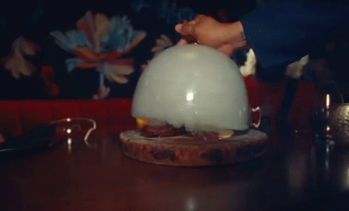 A Person Is Holding A Balloon With Smoke Coming Out Of It On A Table GIF
