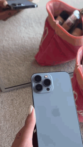 A Person Is Holding A Blue Iphone In Front Of A Mirror GIF
