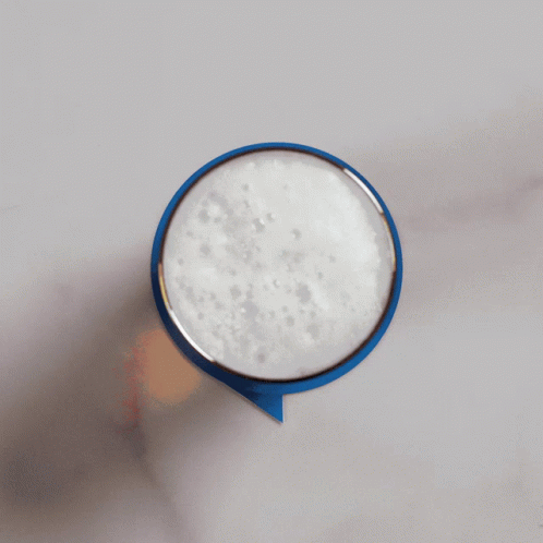 A Person Is Holding A Blue Speech Bubble With Foam On Top GIF
