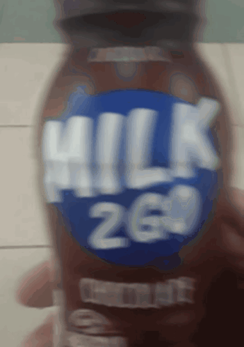 A Person Is Holding A Bottle Of Milk That Has The Number 26 On It GIF