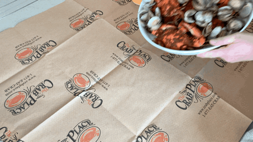 A Person Is Holding A Bowl Of Crawfish On A Crab Place Bag GIF