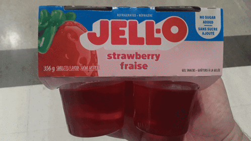 A Person Is Holding A Box Of Strawberry Jello In Their Hand GIF