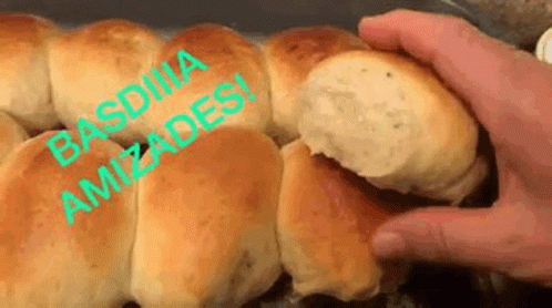 A Person Is Holding A Bun With A Bite Taken Out Of It In Their Hand . GIF