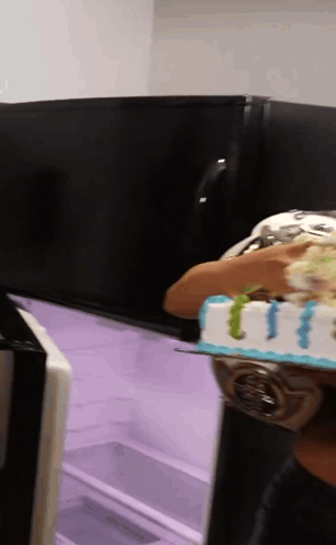 a person is holding a cake in front of a refrigerator