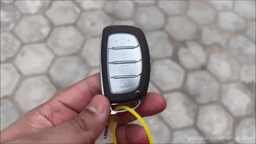 A Person Is Holding A Car Key With A Yellow Tag That Says Youtube.com/namastecar GIF