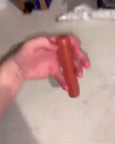 A Person Is Holding A Carrot In Their Hand On A Table . GIF
