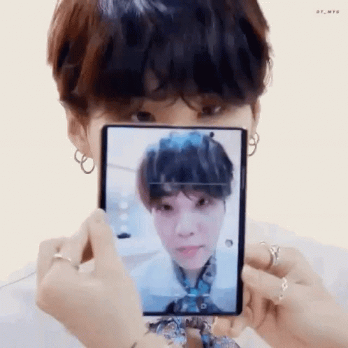 A Person Is Holding A Cell Phone In Front Of Their Face And Taking A Picture Of A Person . GIF