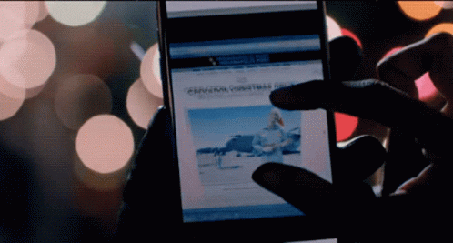 A Person Is Holding A Cell Phone With A Christmas Article On It GIF