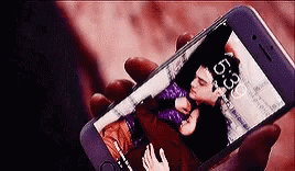 A Person Is Holding A Cell Phone With A Picture Of A Man And A Woman On The Screen . GIF
