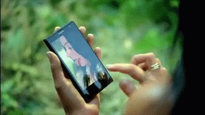 A Person Is Holding A Cell Phone With A Picture Of A Man On The Screen GIF