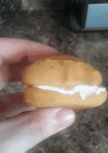 A Person Is Holding A Cookie With Whipped Cream On Top GIF