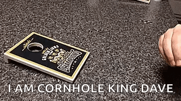 A Person Is Holding A Cornhole Board On A Table . GIF