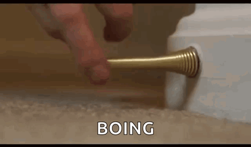A Person Is Holding A Door Stop In Their Hand And Pressing It On A Door . GIF