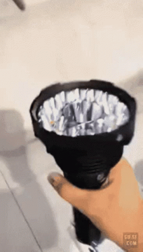 A Person Is Holding A Flashlight In Their Hand And The Flashlight Is Shining Brightly GIF