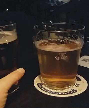 A Person Is Holding A Glass Of Beer On A Coaster That Says The World 'S Oldest Brewing GIF