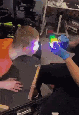 A Person Is Holding A Glow In The Dark Cube In Front Of A Child . GIF