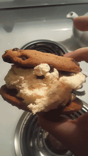 A Person Is Holding A Half Eaten Cookie With Whipped Cream And Chocolate Chips GIF