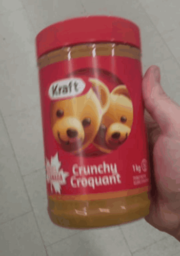 A Person Is Holding A Jar Of Kraft Peanut Butter GIF