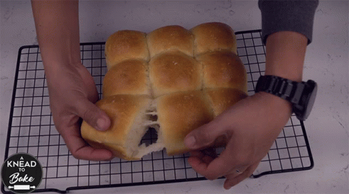 A Person Is Holding A Loaf Of Bread That Says Knead And Bake GIF